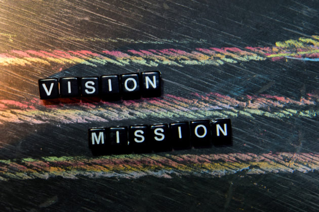 Vision Mission on wooden blocks. Cross processed image with blackboard background. Inspiration, education and motivation concepts